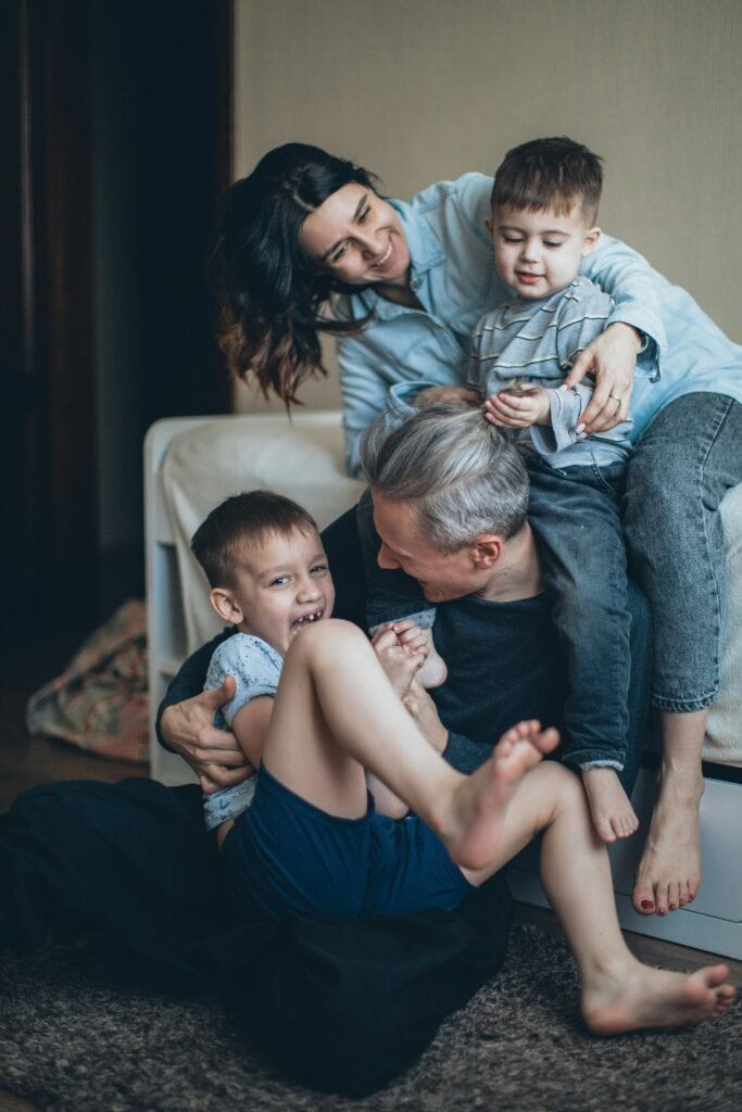 Joyful family of four playing affectionately together indoors, sharing a bonding moment.